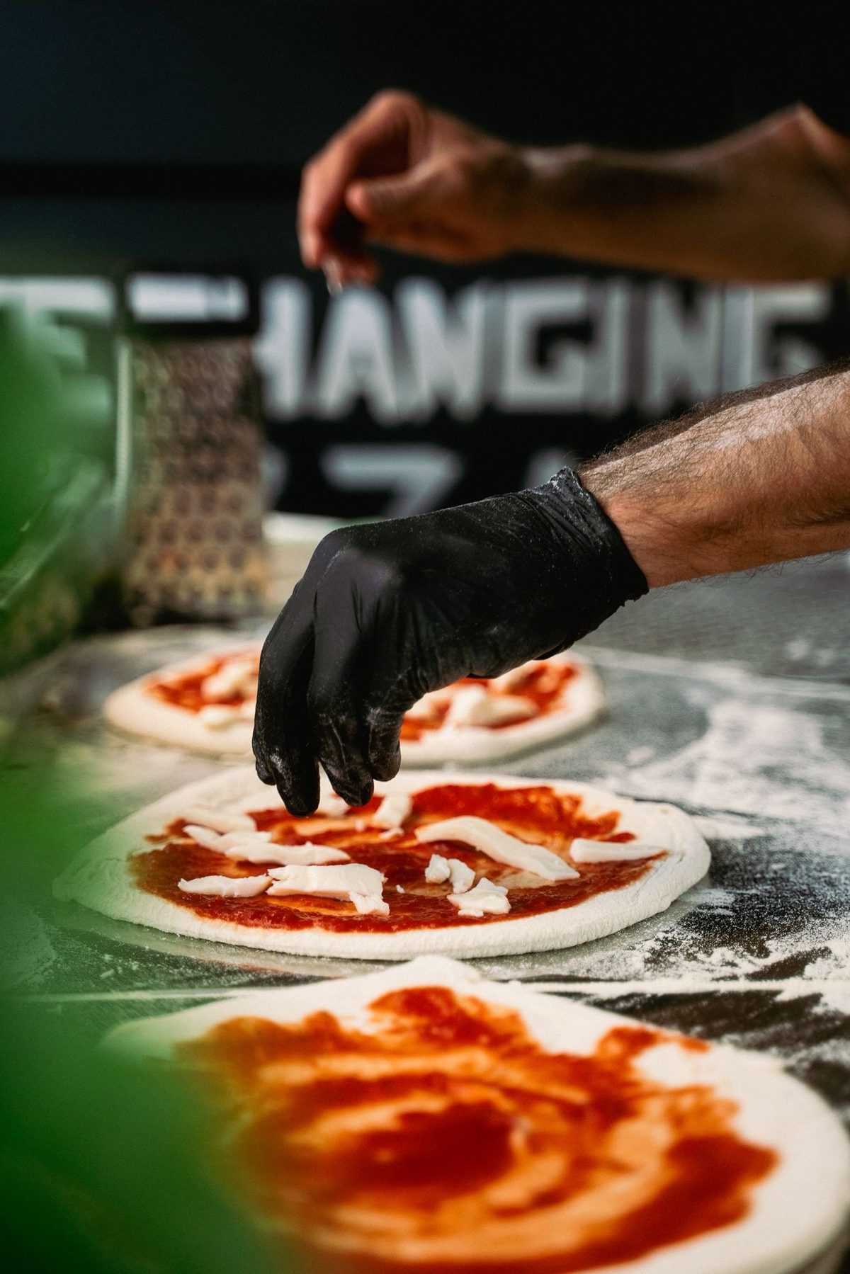 Pizzen werden mit Tomatensauce und Fior di Latte belegt