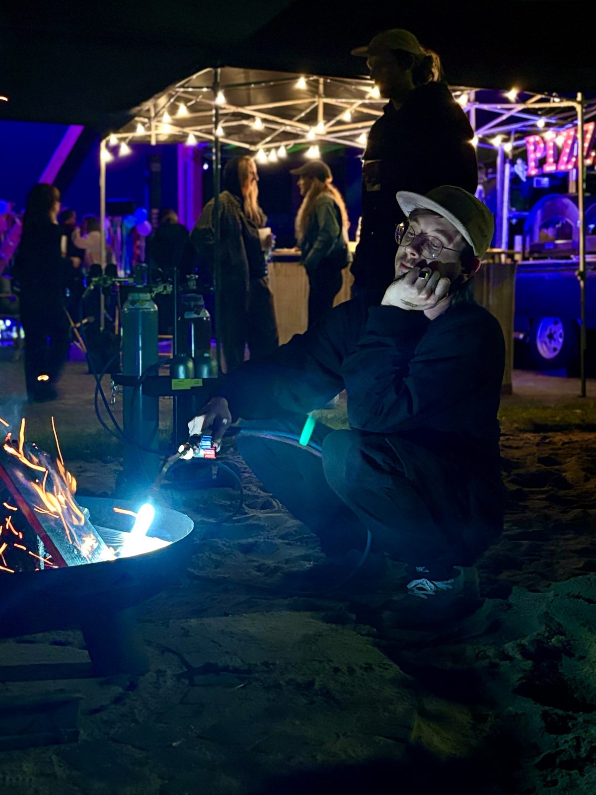 Feuerschale, Lichterketten und Gäste bei einem Abend im Sand
